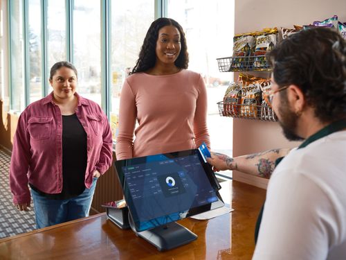 Un caissier montre une tablette à un client qui effectue un paiement dans un commerce.